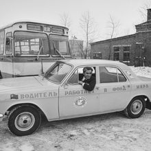 Таксист, сдавший прибыль в Фонд Мира,  за рулем автомобиля "Волга", на заднем плане автобус "3" | Транспорт. 1979 г., г.Северодвинск. Фото #C394.