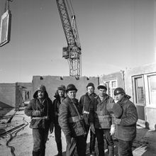 Бригада из шести рабочих на фоне панельной стены строящегося дома | Строительство. 1979 г., г.Северодвинск. Фото #C923.