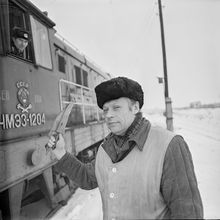 Железнодорожный рабочий с сигнальным флажком | Транспорт. 1984 г., г.Северодвинск. Фото #C1322.